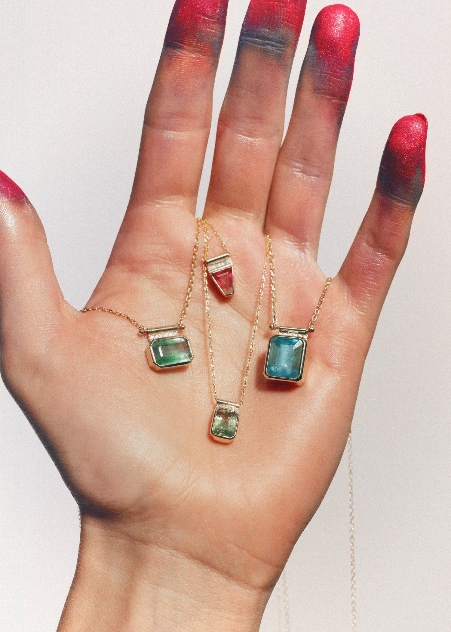 Blue gemstone pendants with diamond bar detail on gold cable chain necklace