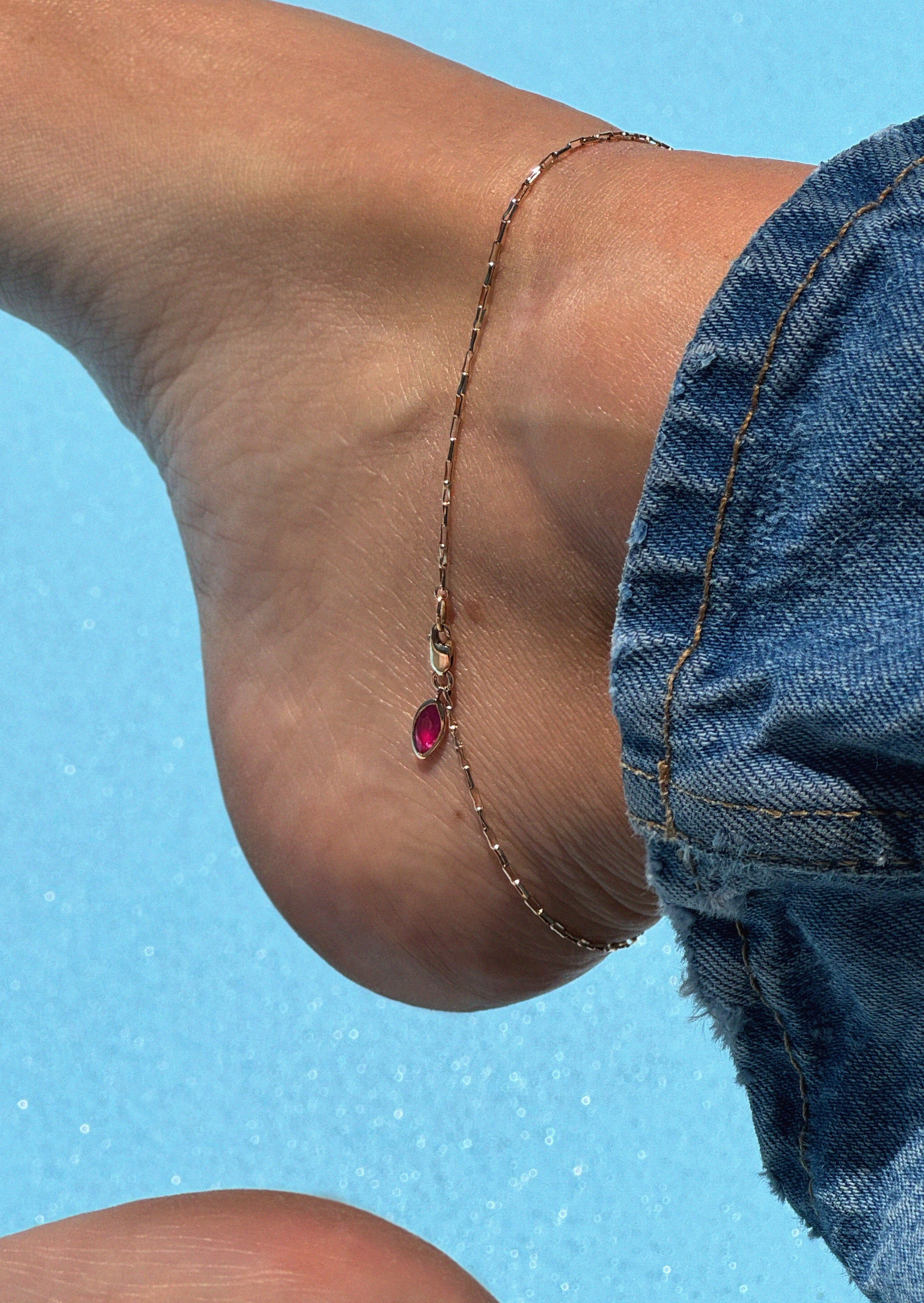 Anklet body jewelry with a ruby charm in 14K yellow gold