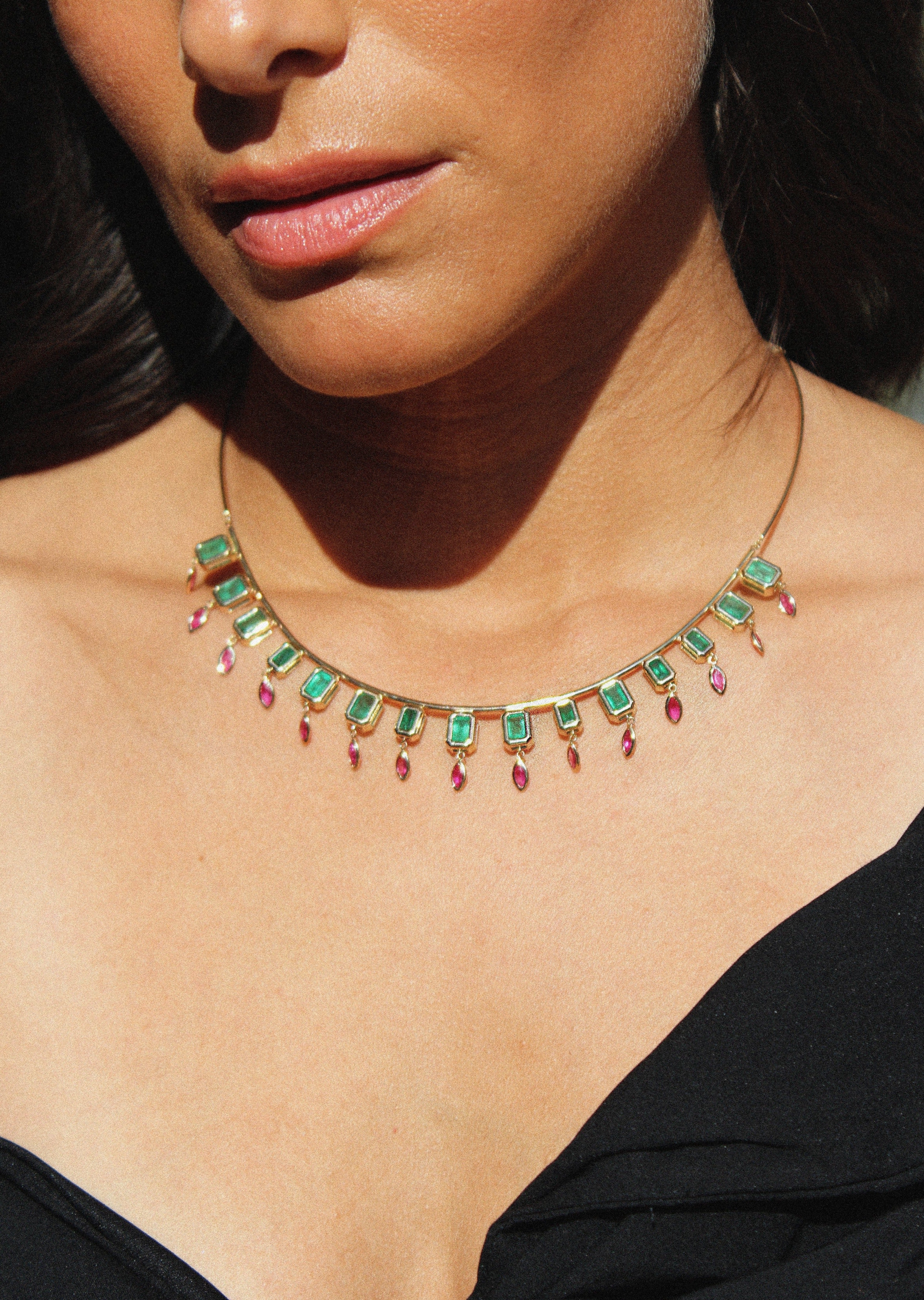 Statement collar necklace featuring emerald-cut emeralds and marquise-shaped pink ruby dangles in 14K yellow gold