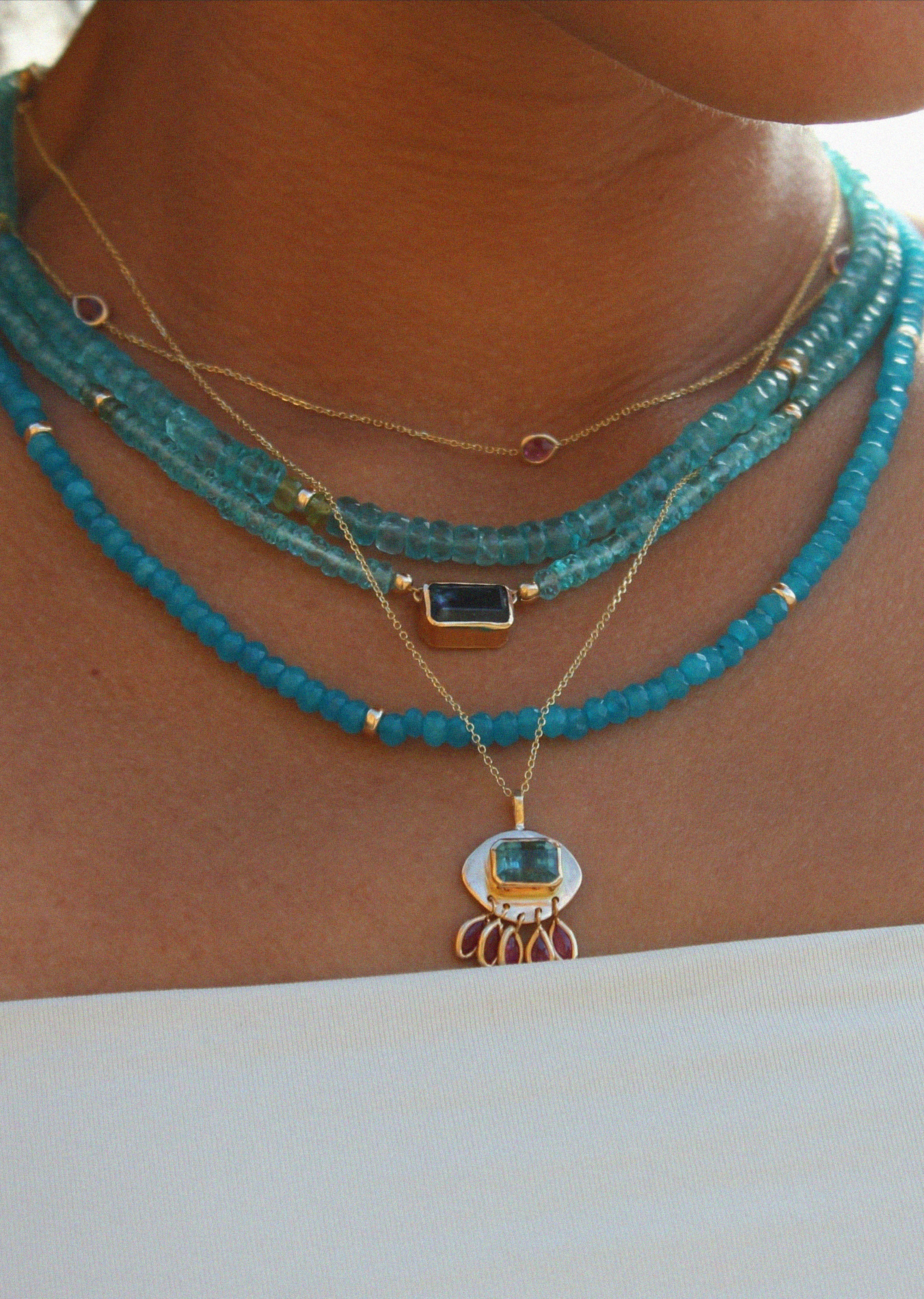 Layered summer jewelry featuring turquoise apatite and gold beads, and a vibrant blue tourmaline pendant