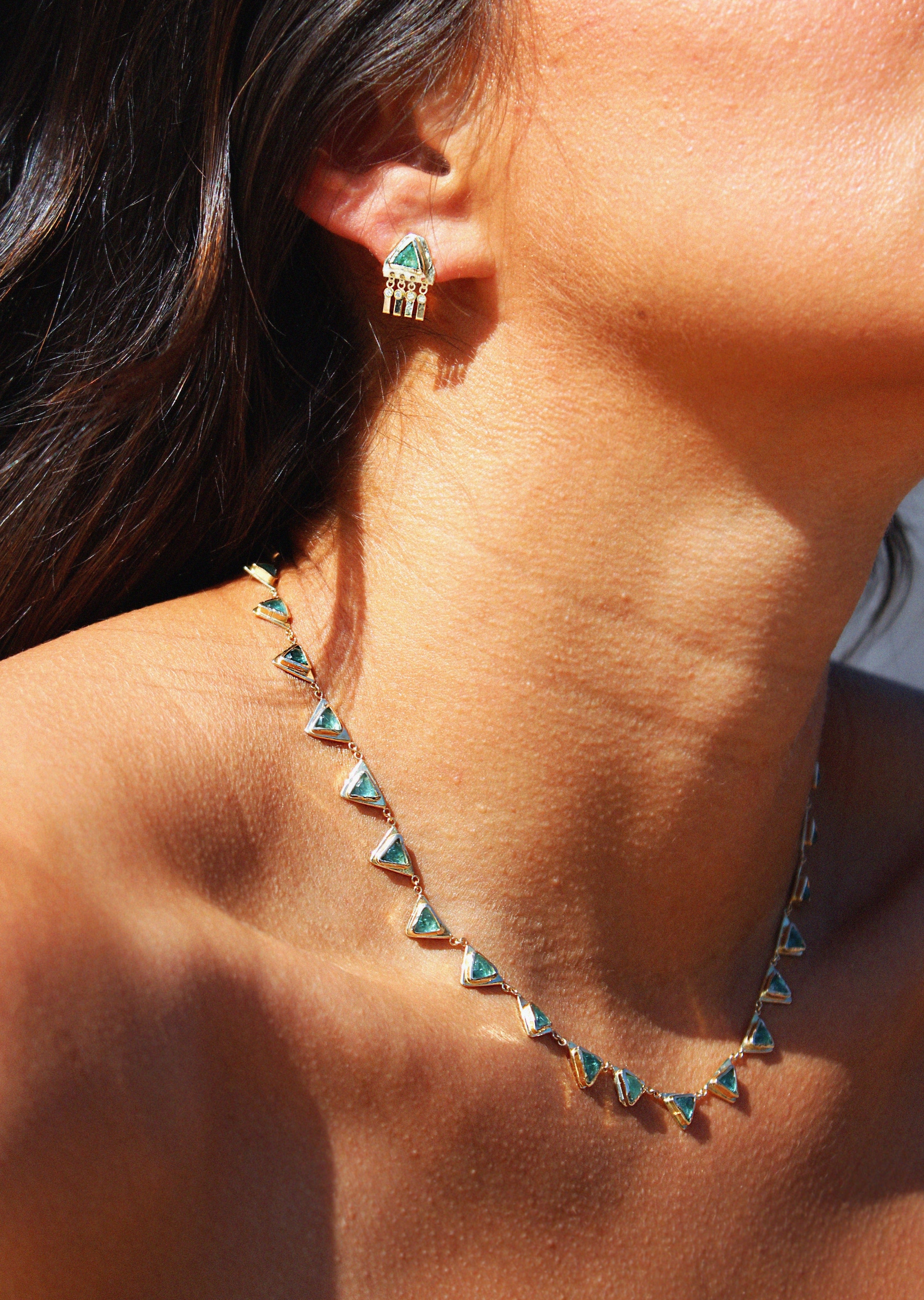 modern tennis necklace featuring trillion-cut emeralds set in 14K yellow gold bezels