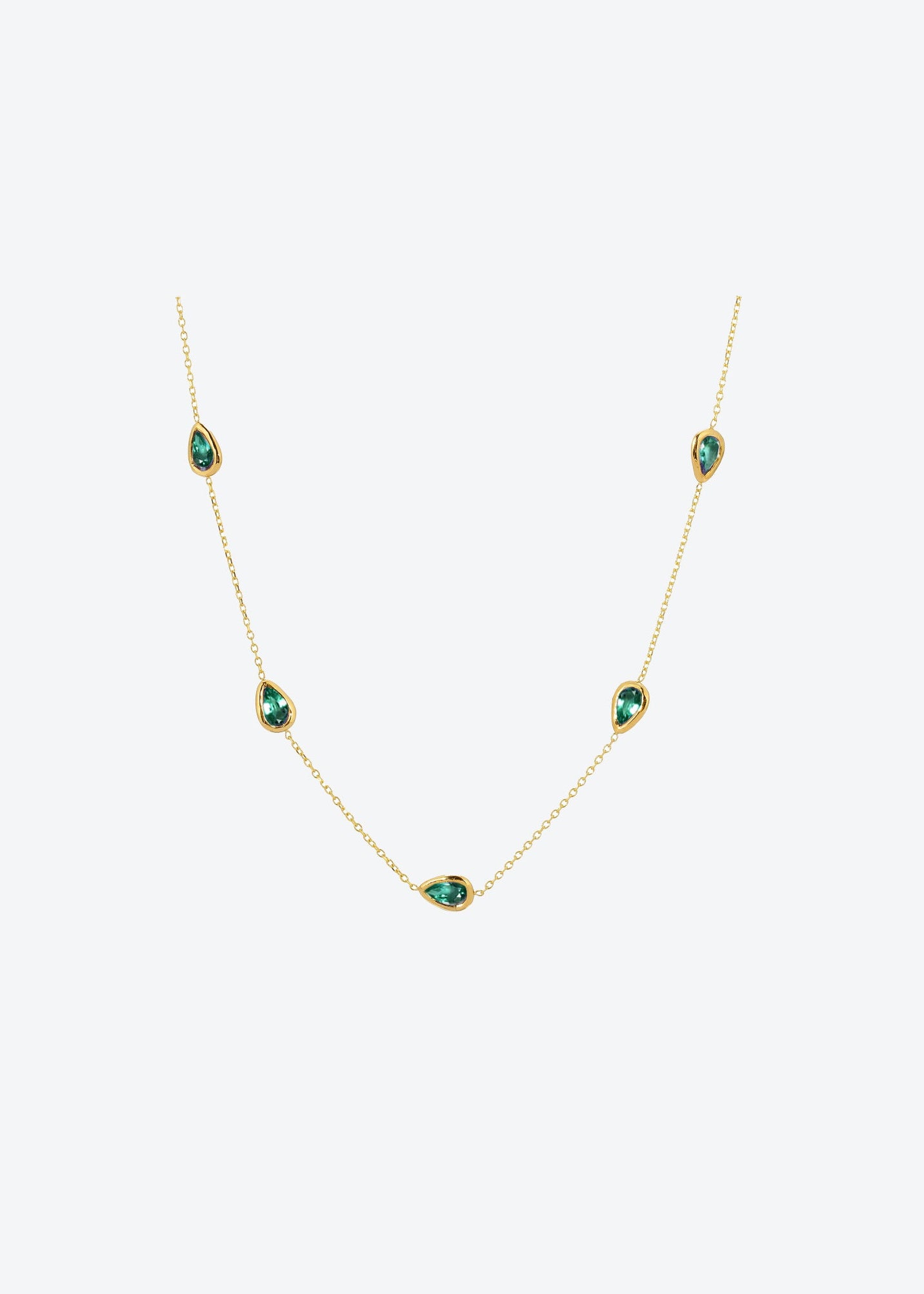Gold necklace with green gemstones on a white background