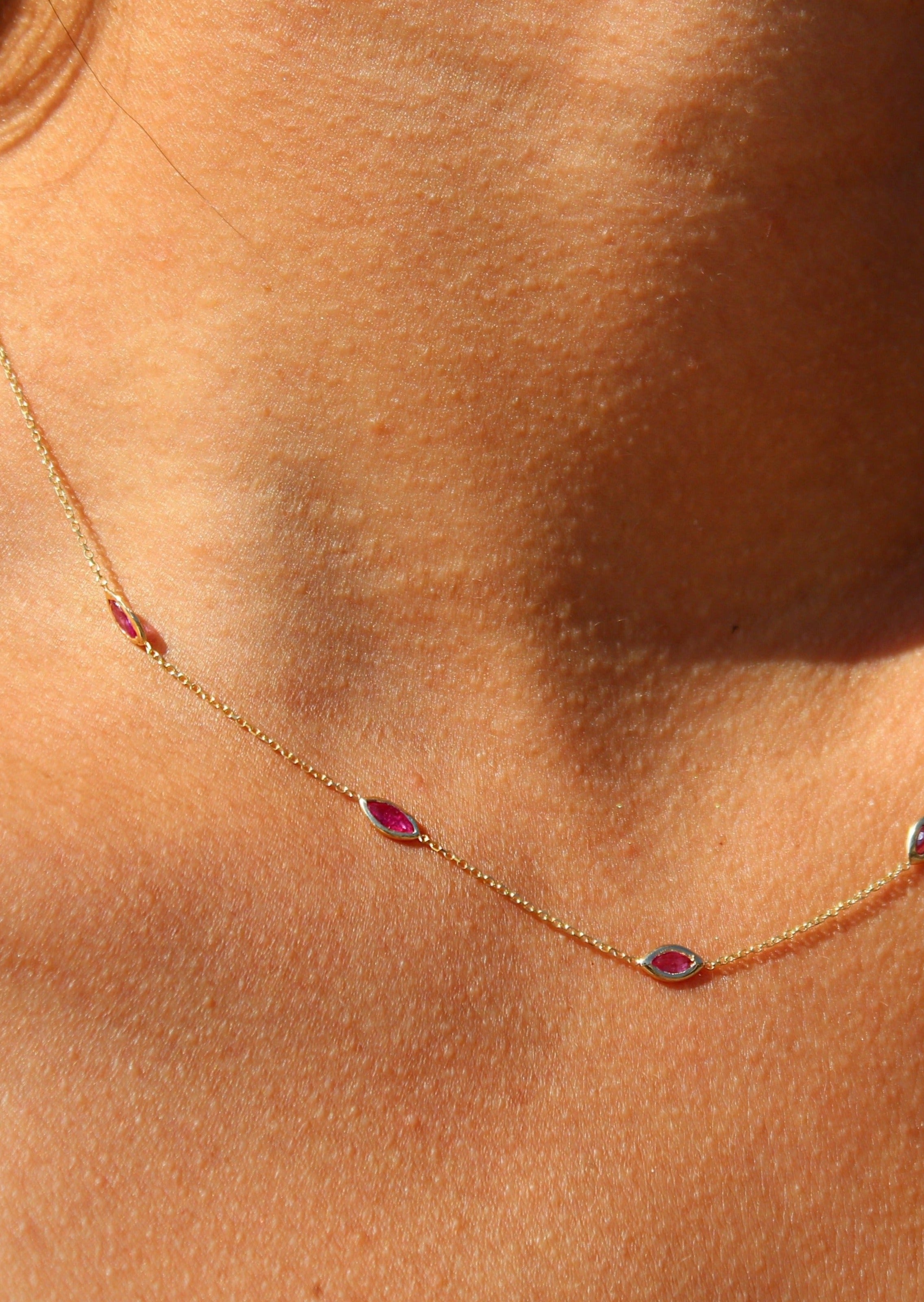 Close-up of bezel-set rubies on delicate cable chain necklace