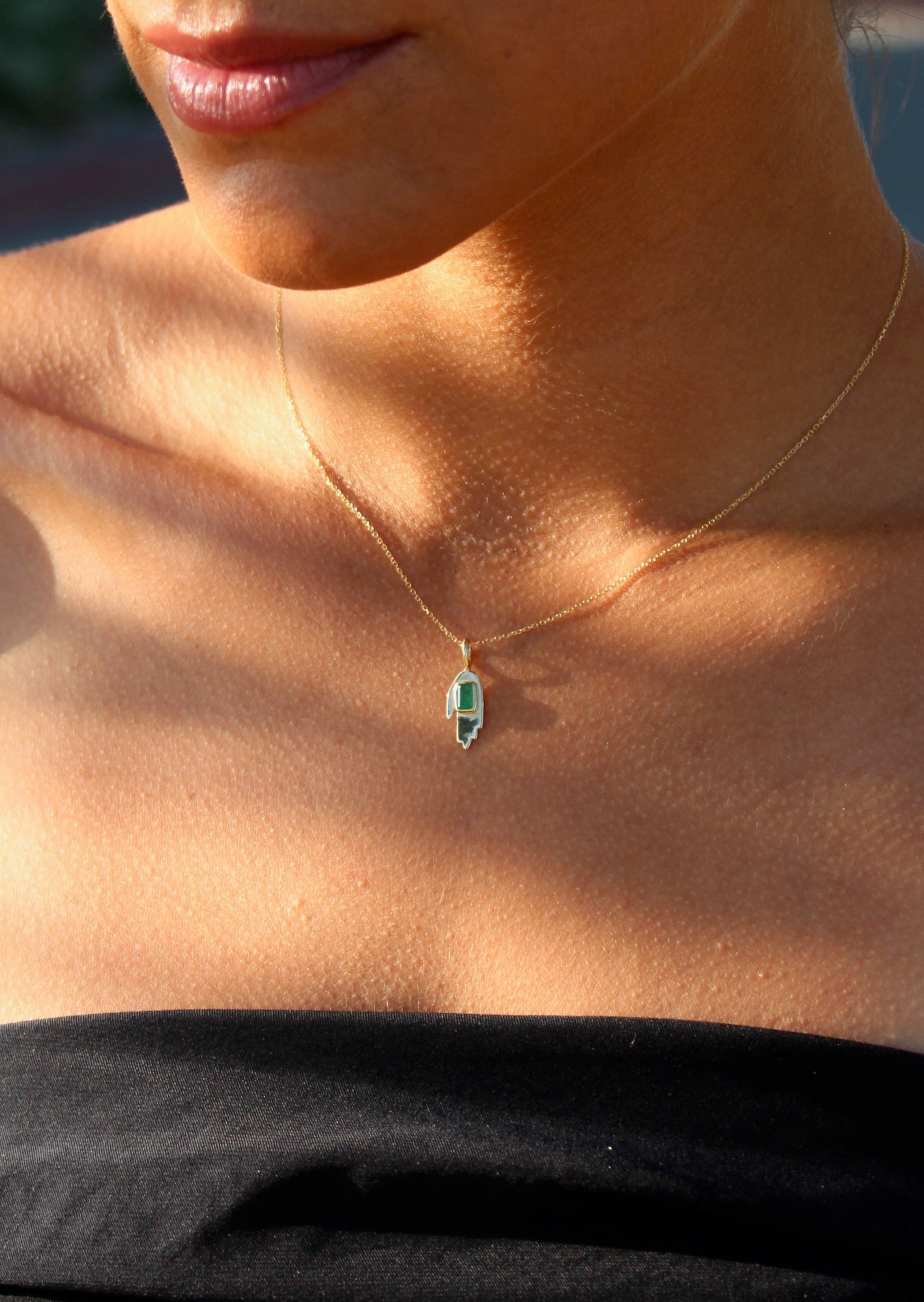 Emerald hand pendant necklace with bezel-set emerald in 14K yellow gold