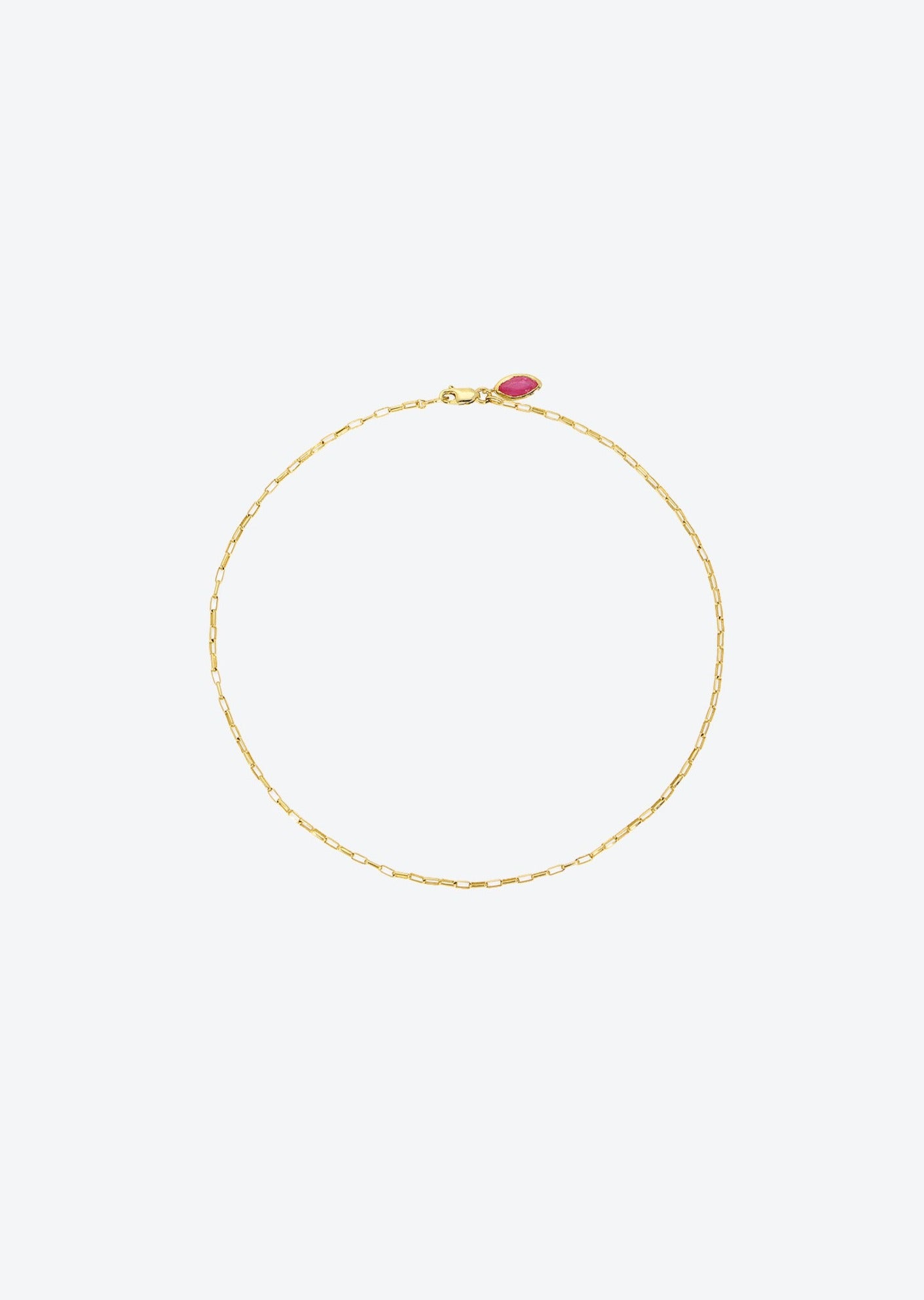 A 14K gold anklet with a delicate paperclip chain and ruby charm, perfect for everyday wear or as summer jewelry.