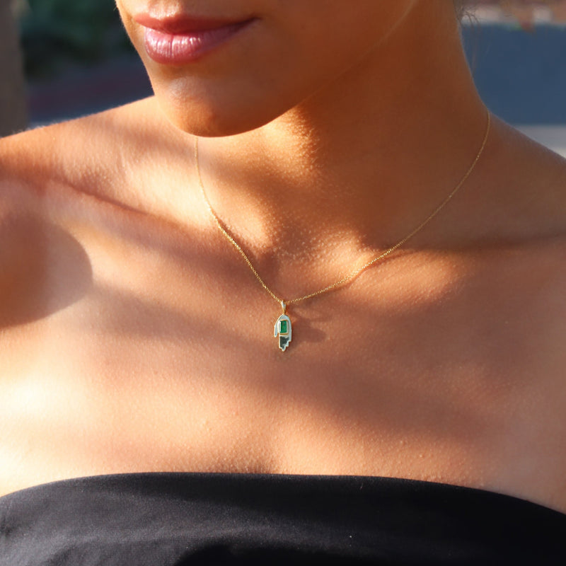 woman wearing small hand pendant with emerald