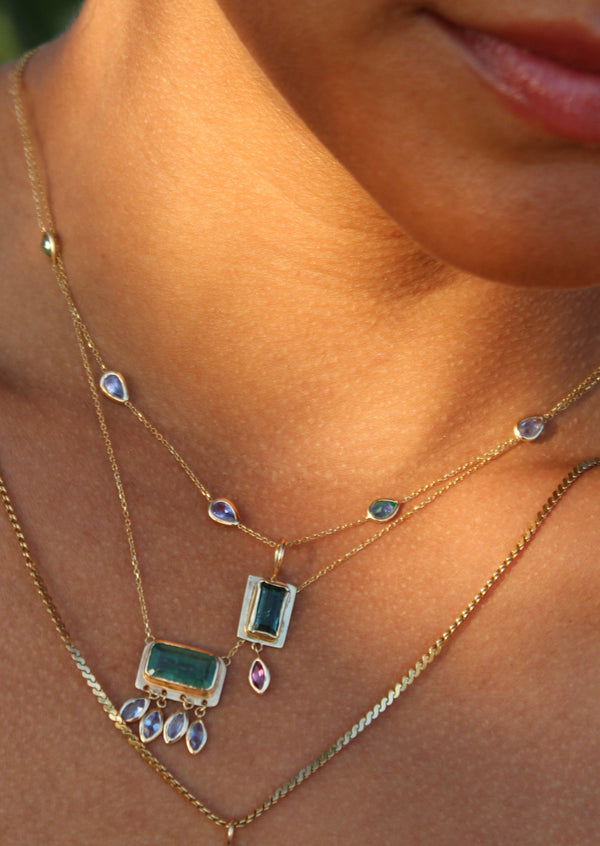 woman wearing dainty necklace with pear shaped blue stones