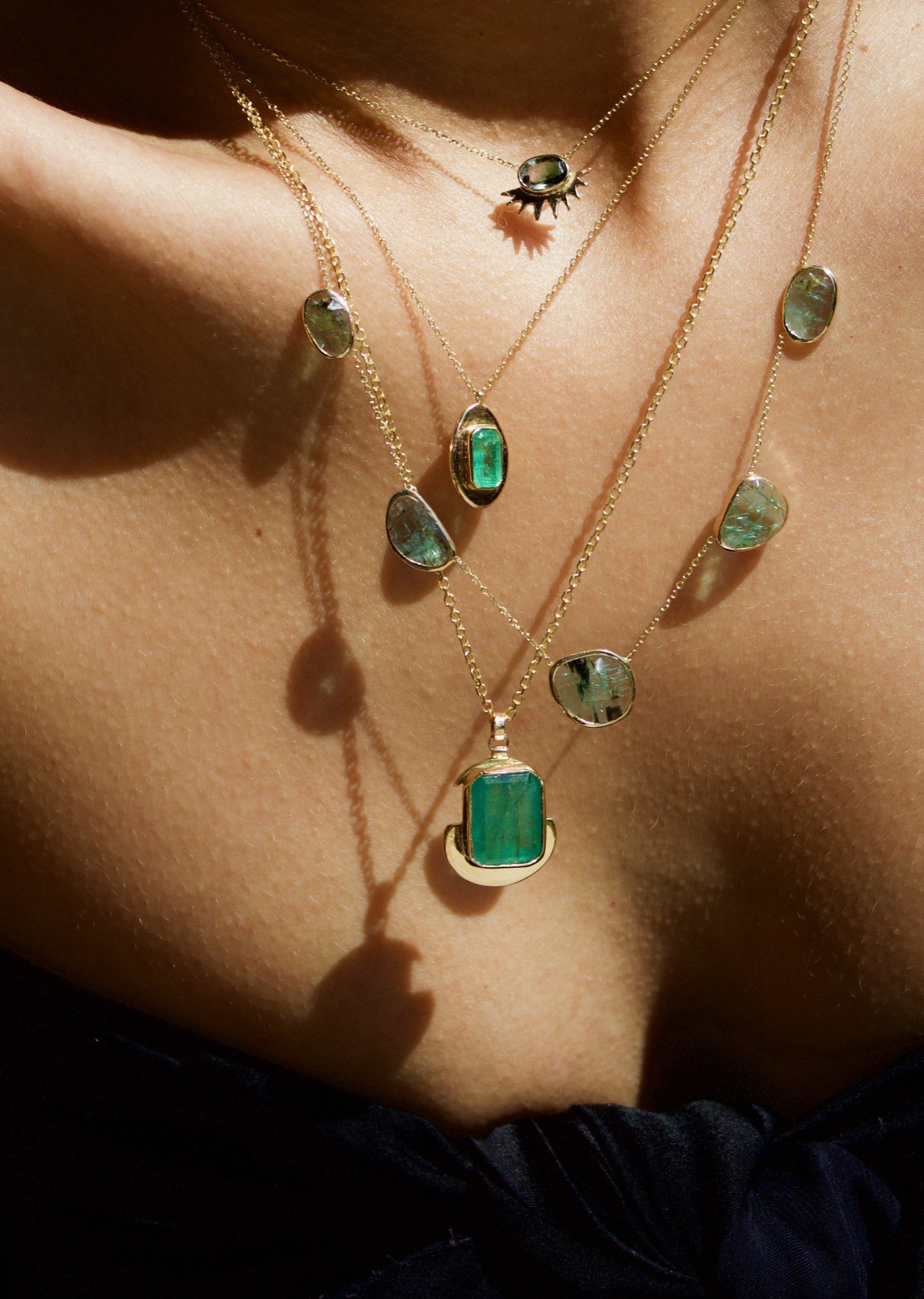 Emerald pendant necklace featuring a sculptural bezel in solid gold, inspired by Aztec jewelry and coin designs.